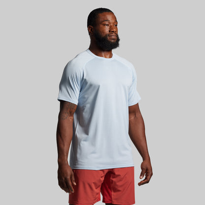Man wearing a light blue t-shirt and red shorts on a gray background
