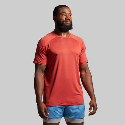 Man wearing a red t-shirt and blue shorts on a gray background
