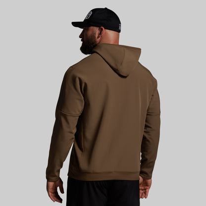 Man wearing a brown hoodie and black cap on a gray background