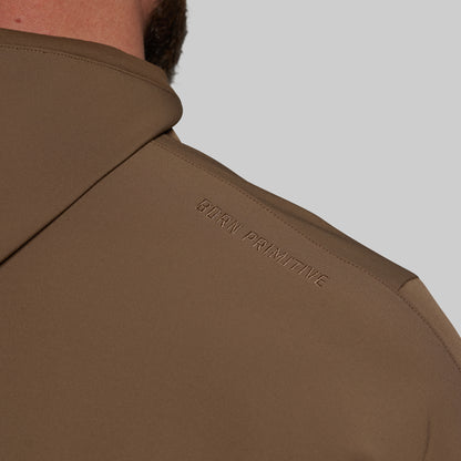 Brown jacket with 'Born Primitive' branding on a gray background