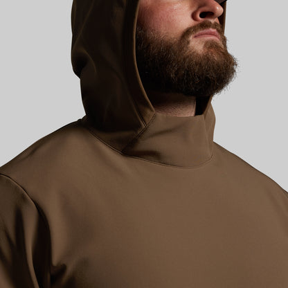 Man wearing a brown hooded jacket against a gray background