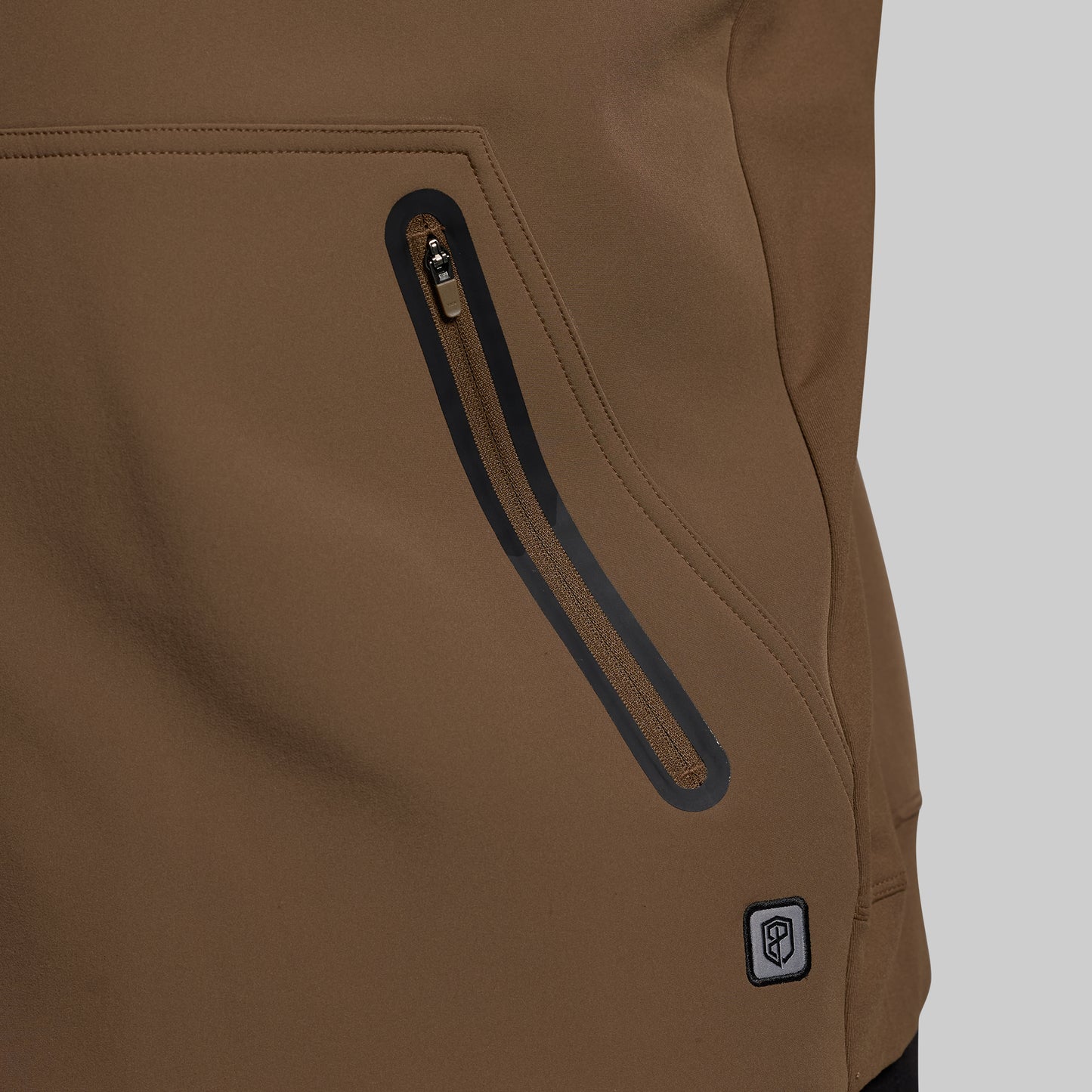 Close-up of a brown jacket with a zipper and brand logo on a gray background