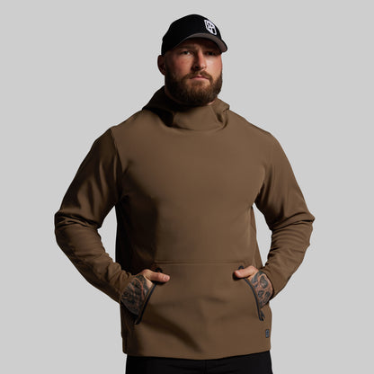Man wearing a brown hoodie and black cap on a gray background