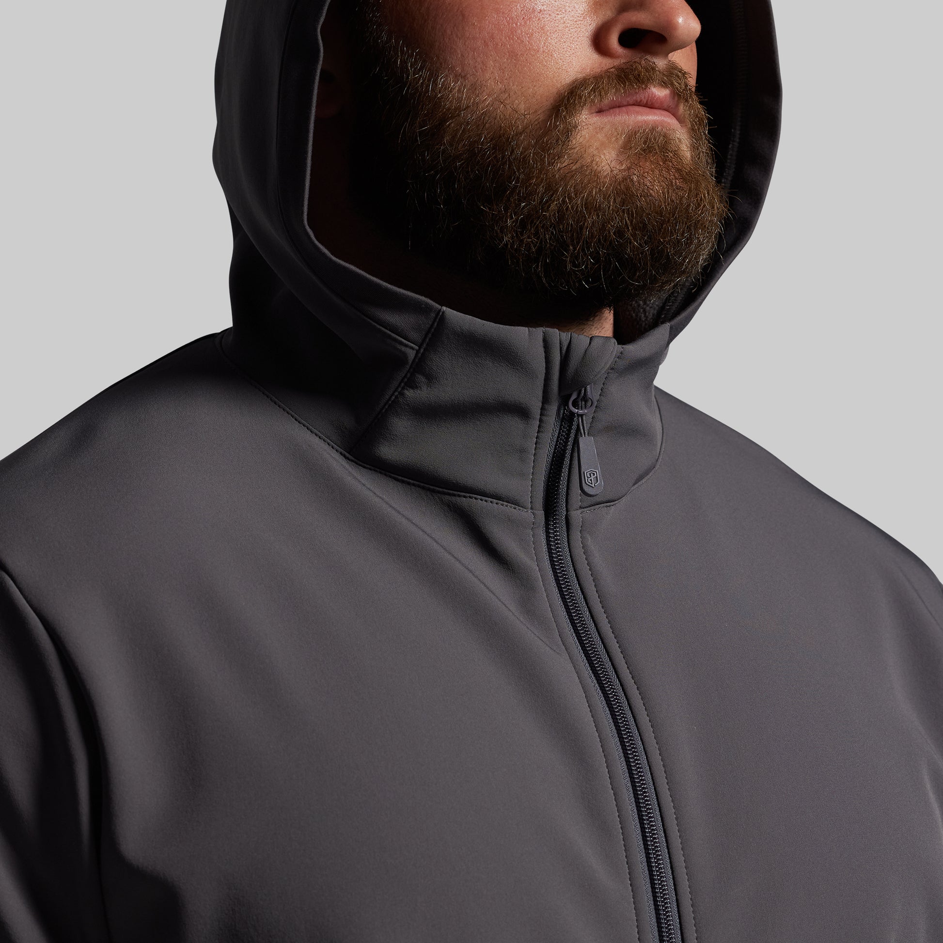 Person wearing a gray hooded jacket on a light gray background
