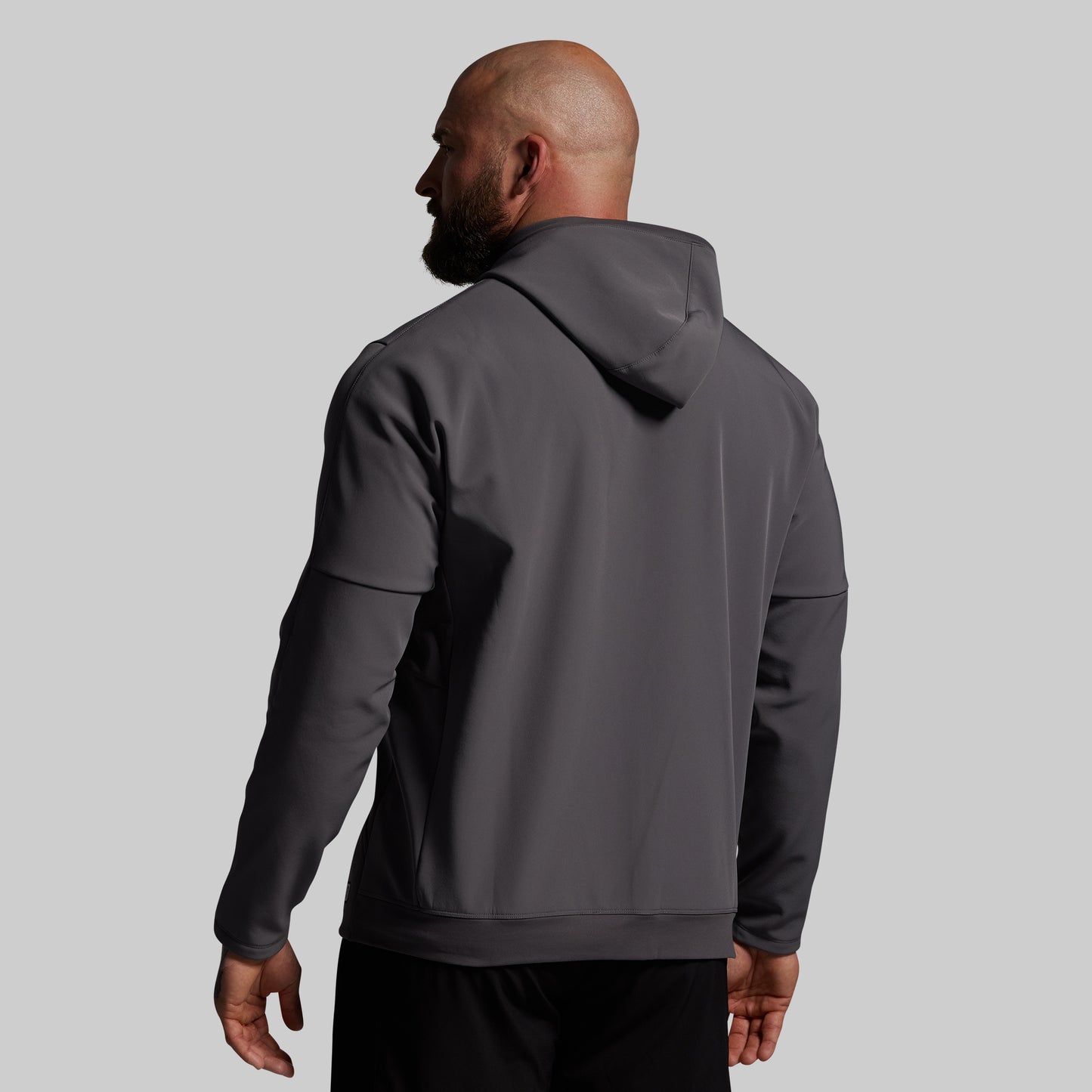 Man wearing a gray hoodie from behind on a light gray background