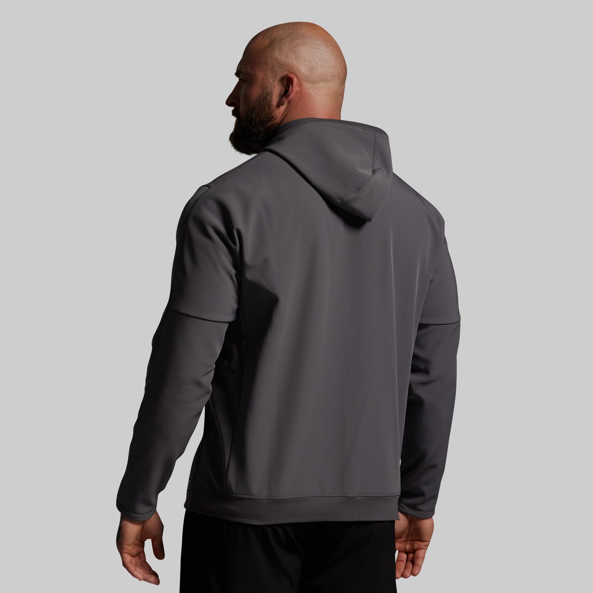 Man wearing a gray hoodie from behind on a light gray background