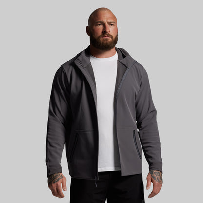 Man wearing a gray full zip hoodie over a white shirt on a gray background