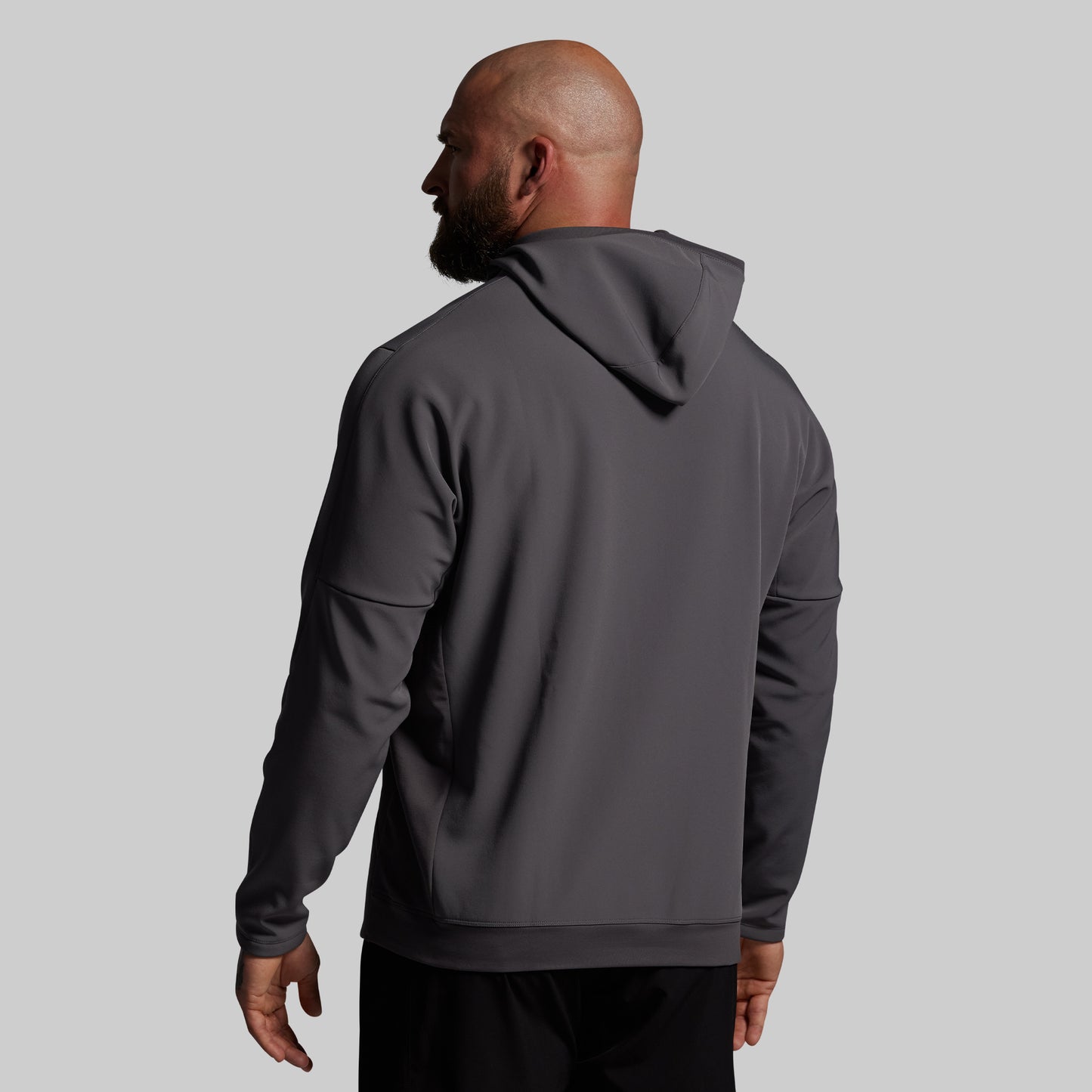 Man wearing a gray hoodie from behind on a light gray background