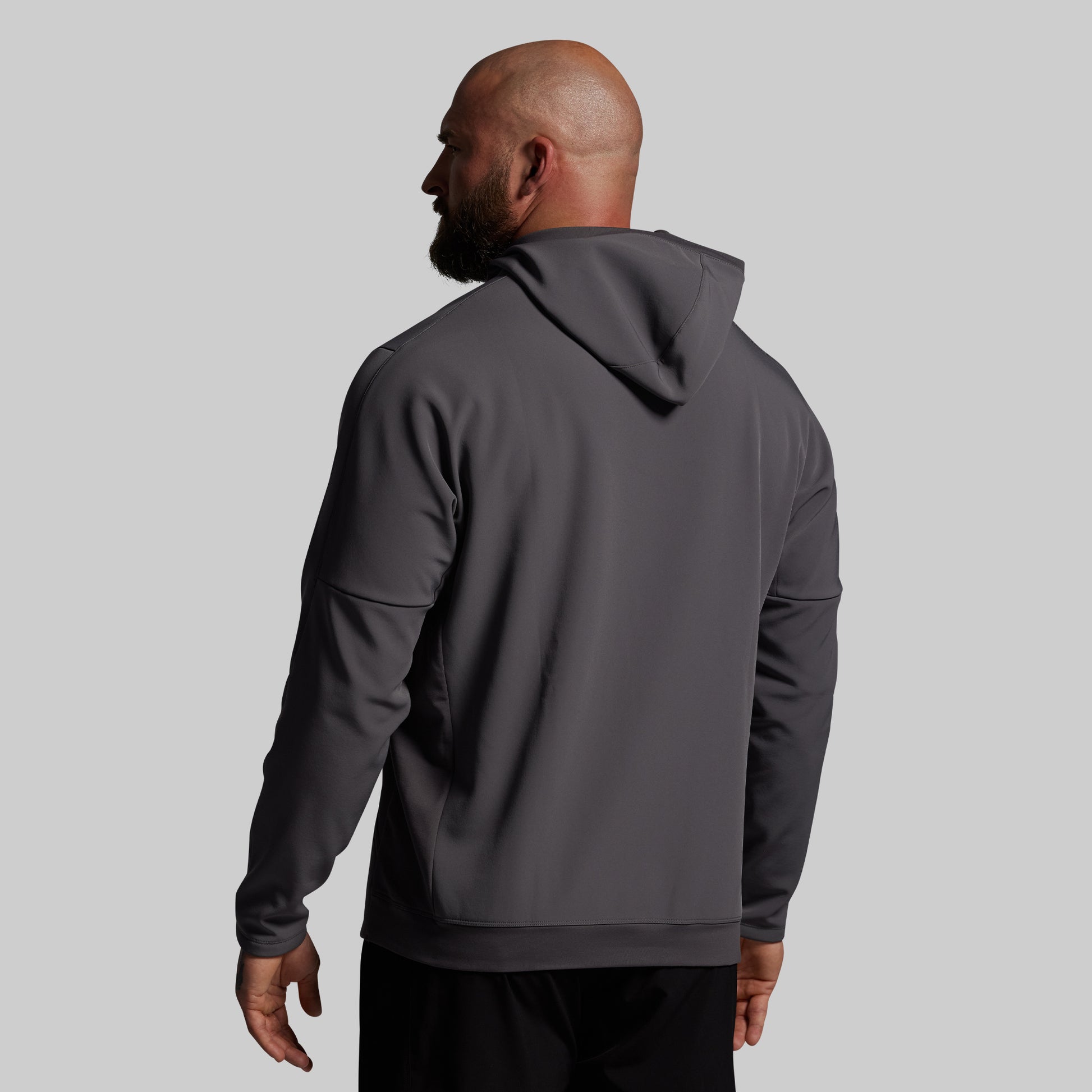 Man wearing a gray hoodie from behind on a light gray background