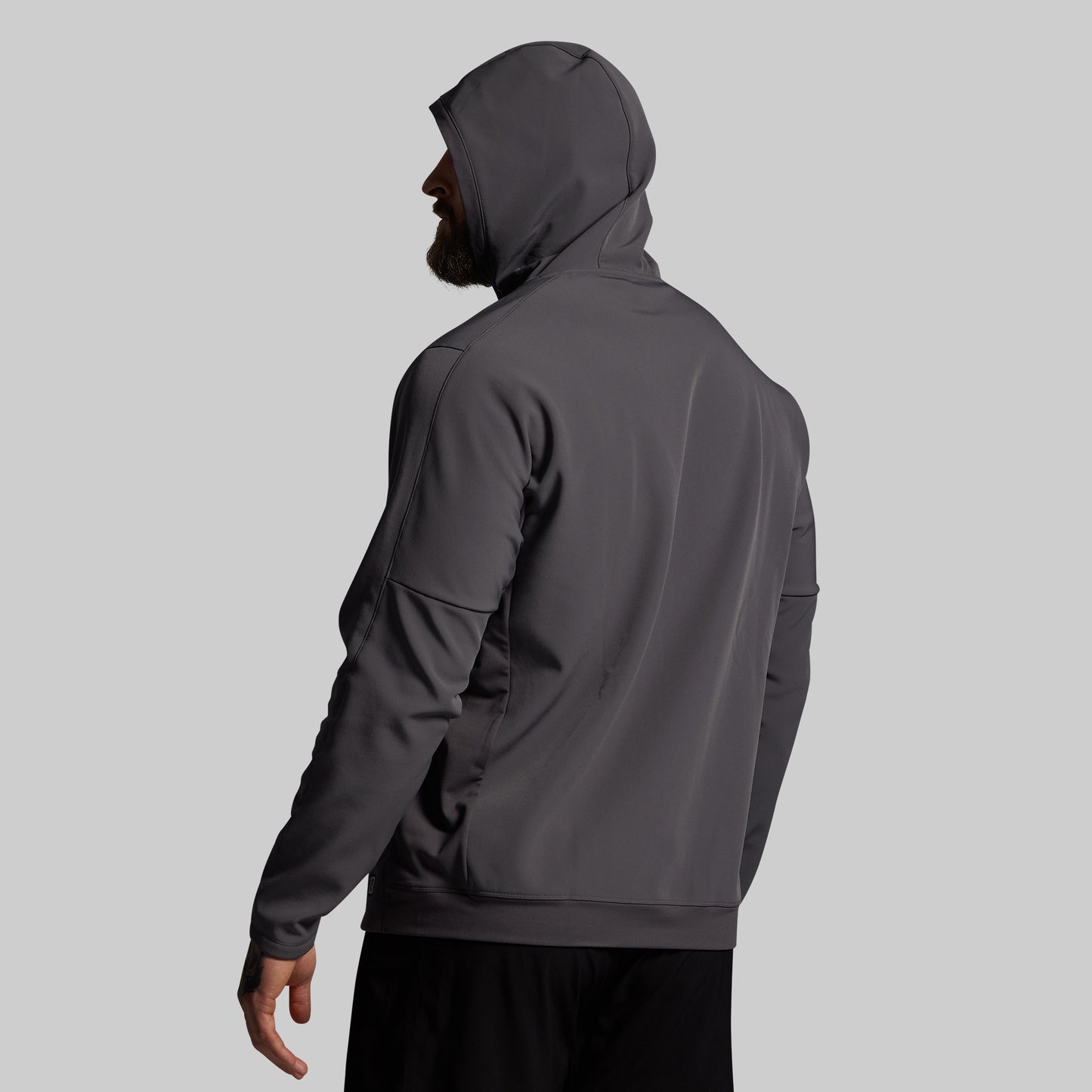 Person wearing a dark gray hoodie on a light gray background