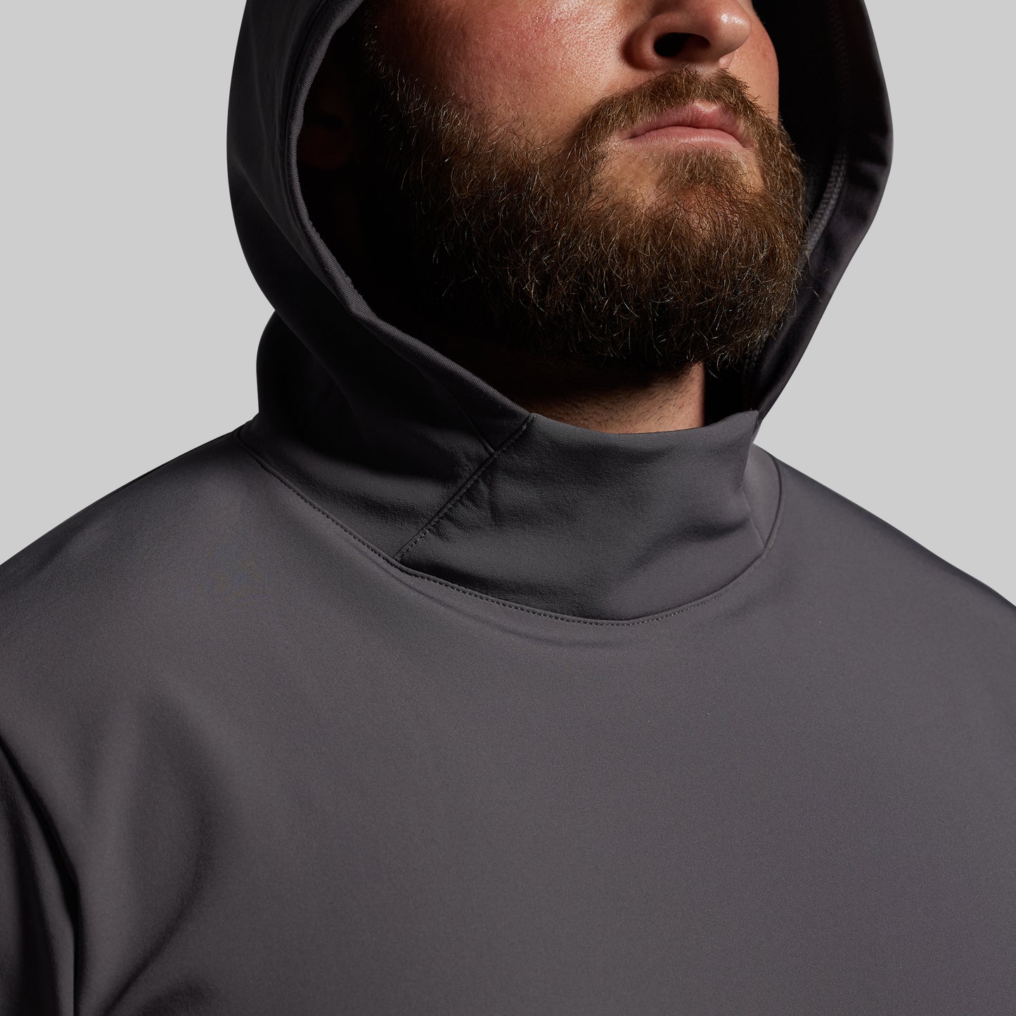Person wearing a dark gray hoodie against a light gray background