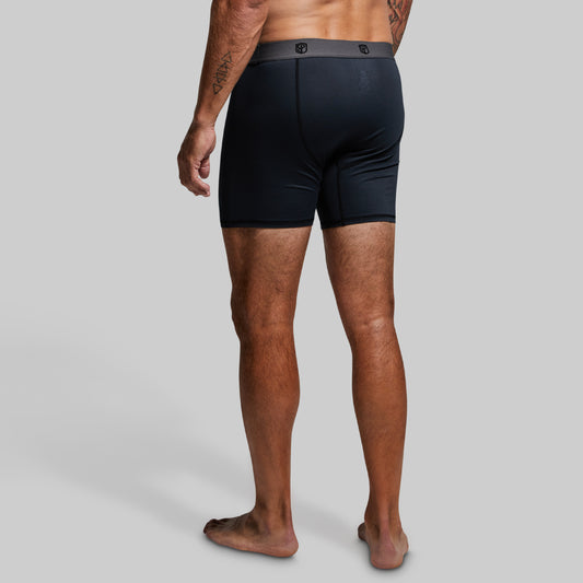 Man wearing black boxer briefs on a gray background