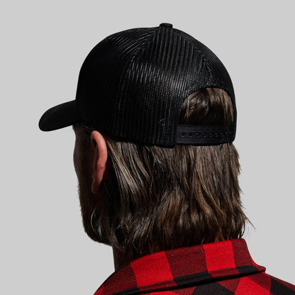 Person wearing a black mesh cap and red plaid shirt on a gray background