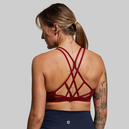 Person wearing a red sports bra with criss-cross straps on a gray background