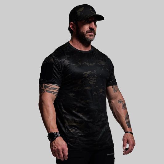 Man wearing a black camouflage t-shirt and cap on a gray background