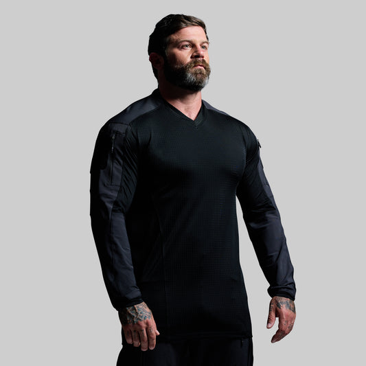 Man wearing a black long-sleeve shirt against a gray background