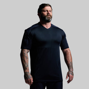 Man wearing a blue tactical t-shirt against a gray background