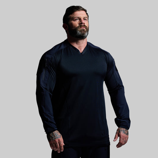 Man wearing a dark blue long-sleeve shirt against a gray background