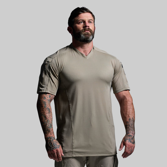 Man wearing a beige tactical shirt on a gray background