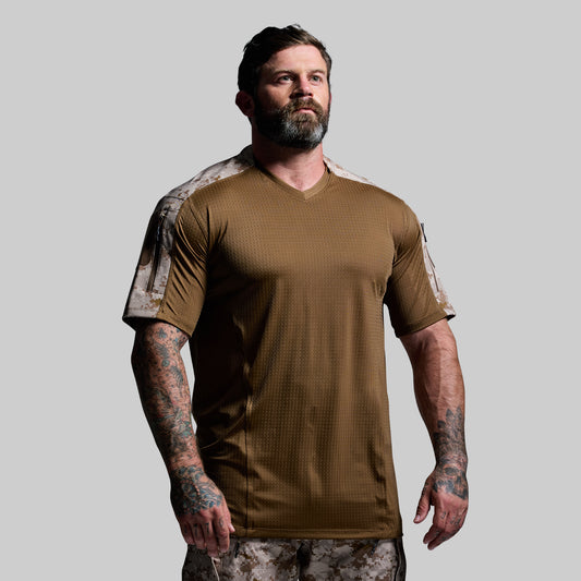 Man wearing a brown tactical shirt with camouflage sleeves on a gray background