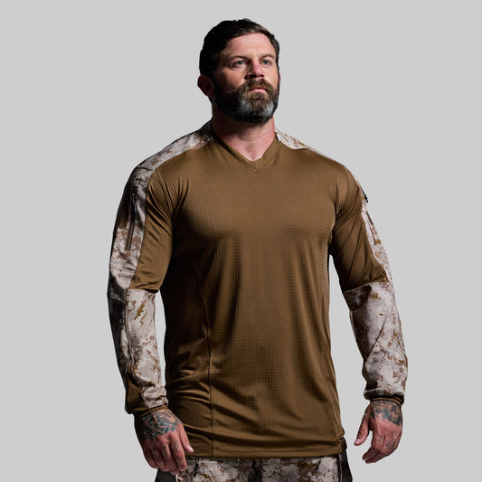 Man wearing a brown long-sleeve shirt with camouflage sleeves on a gray background