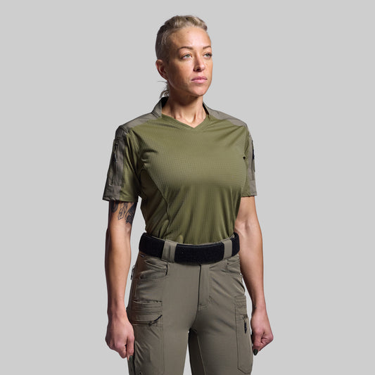 Person wearing an olive green shirt and beige pants on a gray background