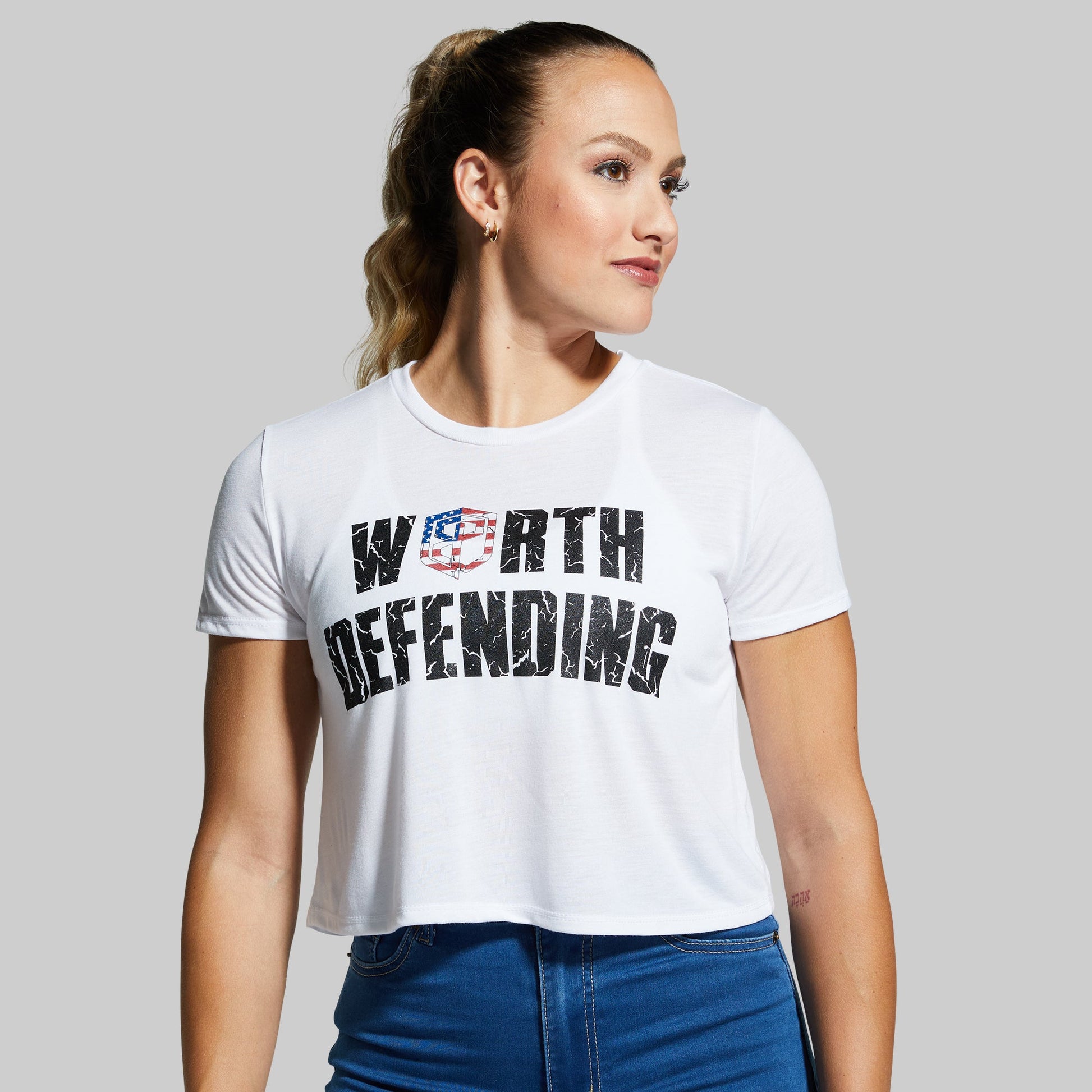 Woman wearing a white t-shirt with 'Worth Defending' text on a gray background