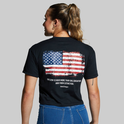 Person wearing a black t-shirt with an American flag design on the back against a gray background