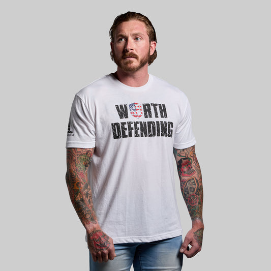Man wearing a white t-shirt with 'Worth Defending' text and American flag design on a gray background