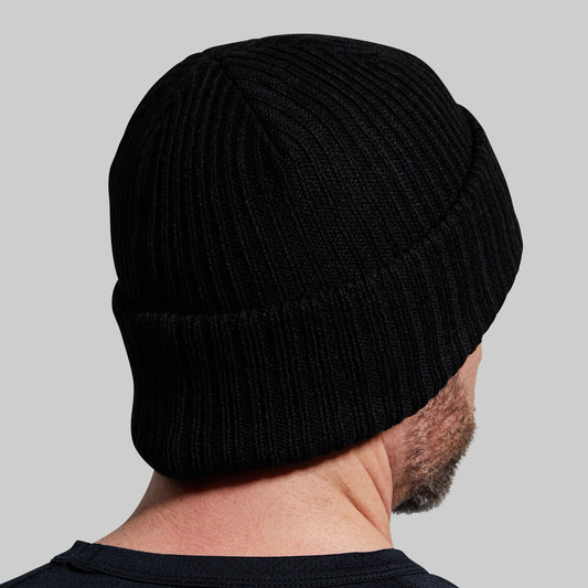 Back view of a man wearing a black beanie against a gray background