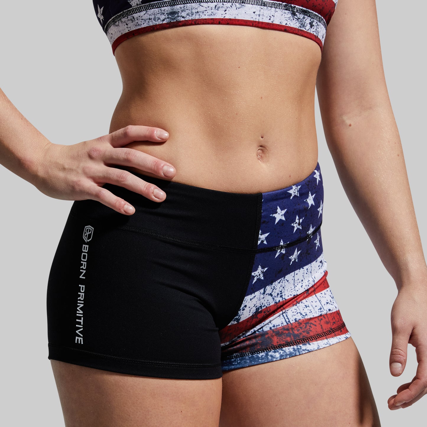 Person wearing black and American flag patterned shorts on a plain background
