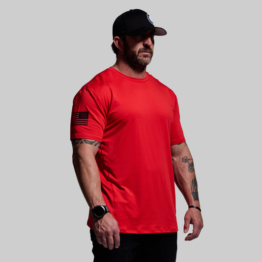 Man wearing a red t-shirt and black cap on a gray background