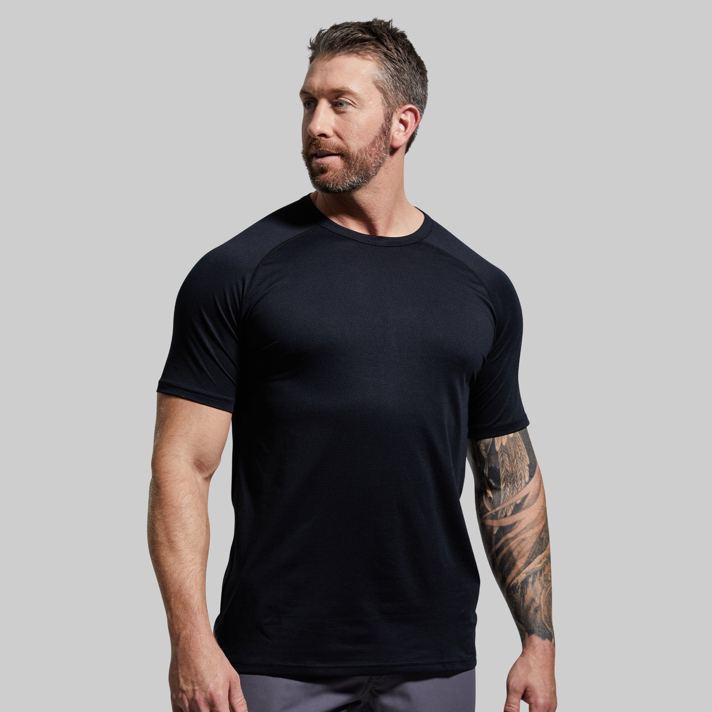 Man wearing a black t-shirt against a gray background