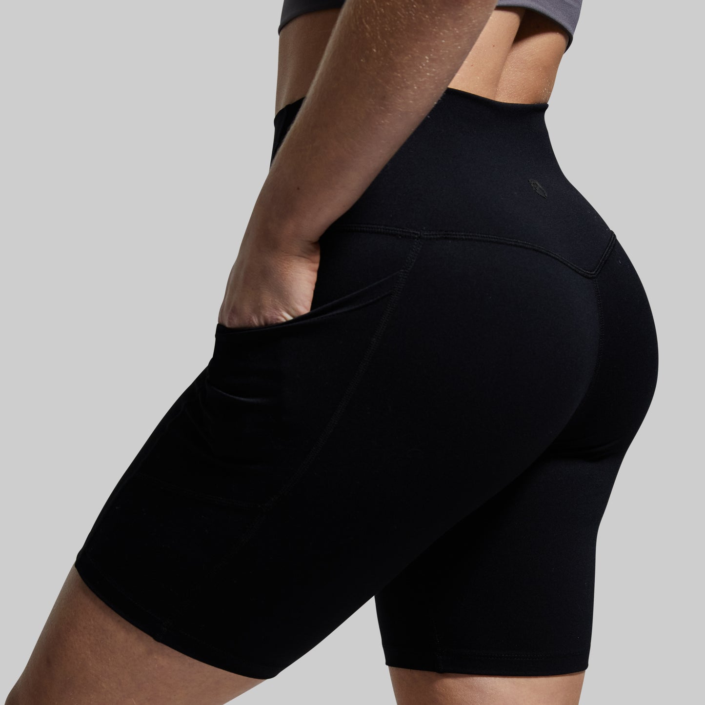Person wearing black athletic shorts on a plain background