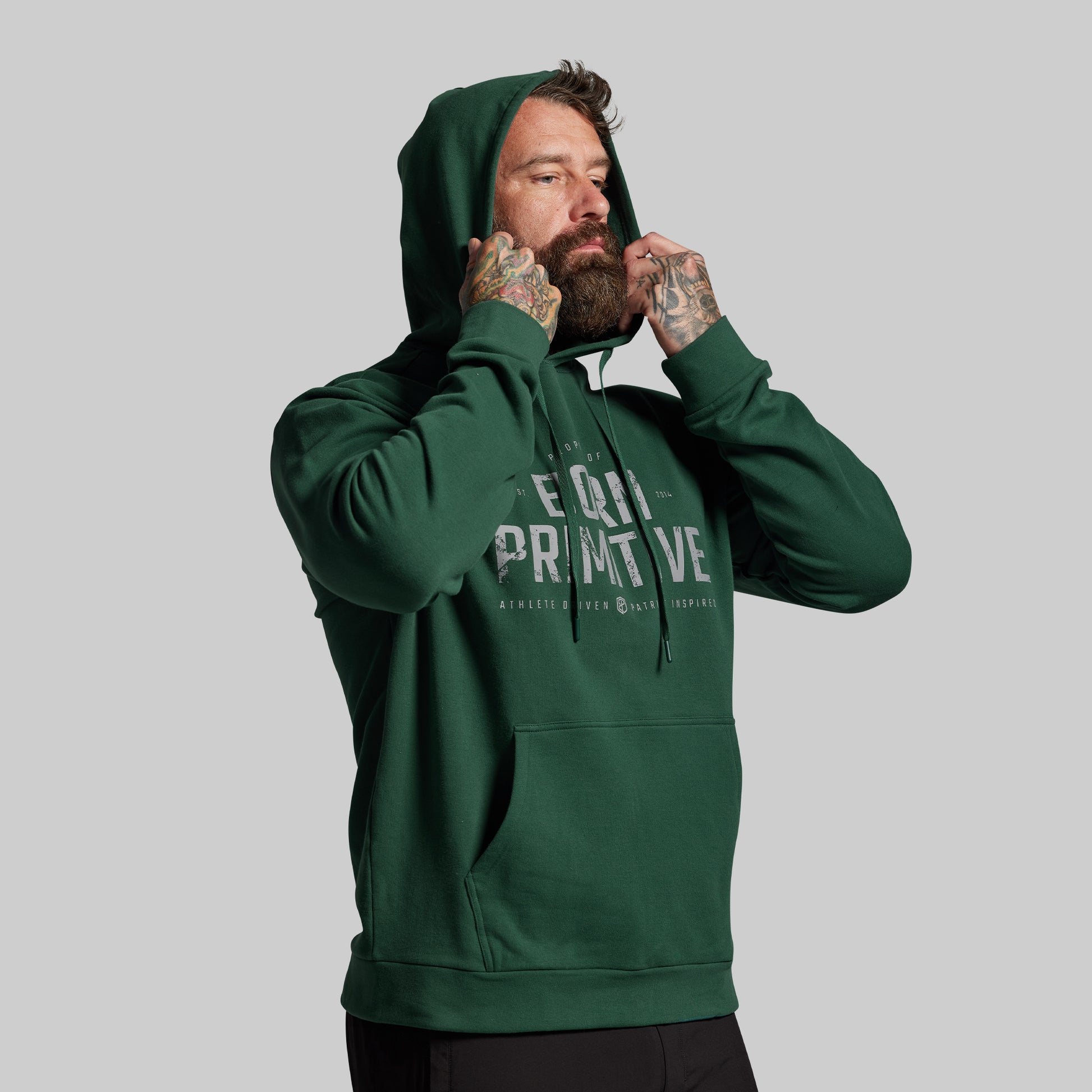 Man wearing a green hoodie with visible branding on a gray background
