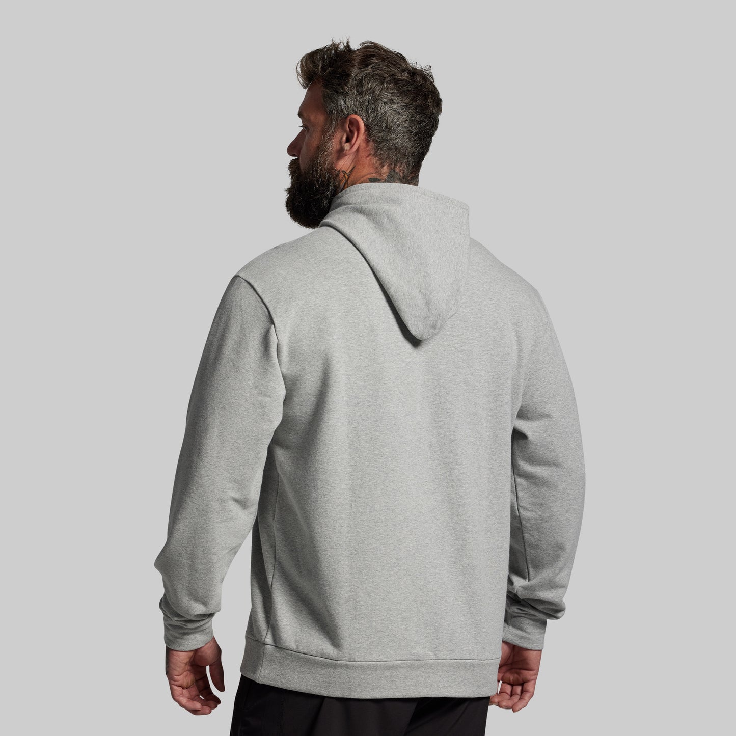 Man wearing a gray hoodie from behind on a light gray background