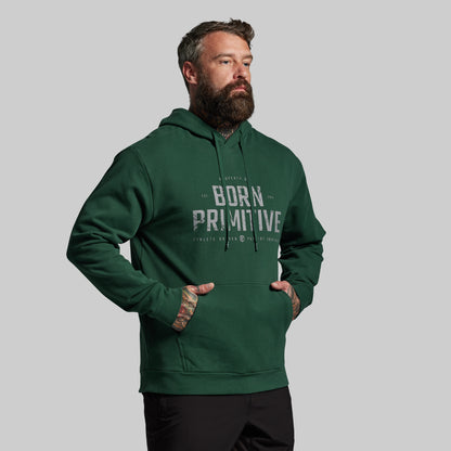 Man wearing a green hoodie with 'Born Primitive' text on a gray background