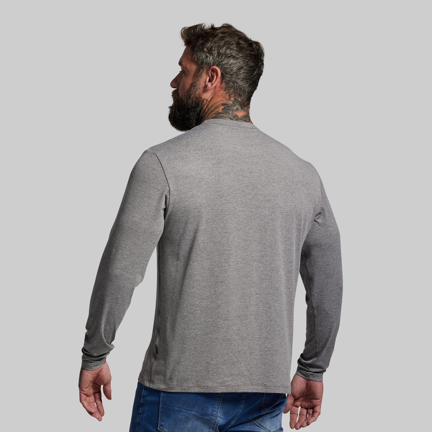 Man wearing a gray long-sleeve shirt against a light gray background