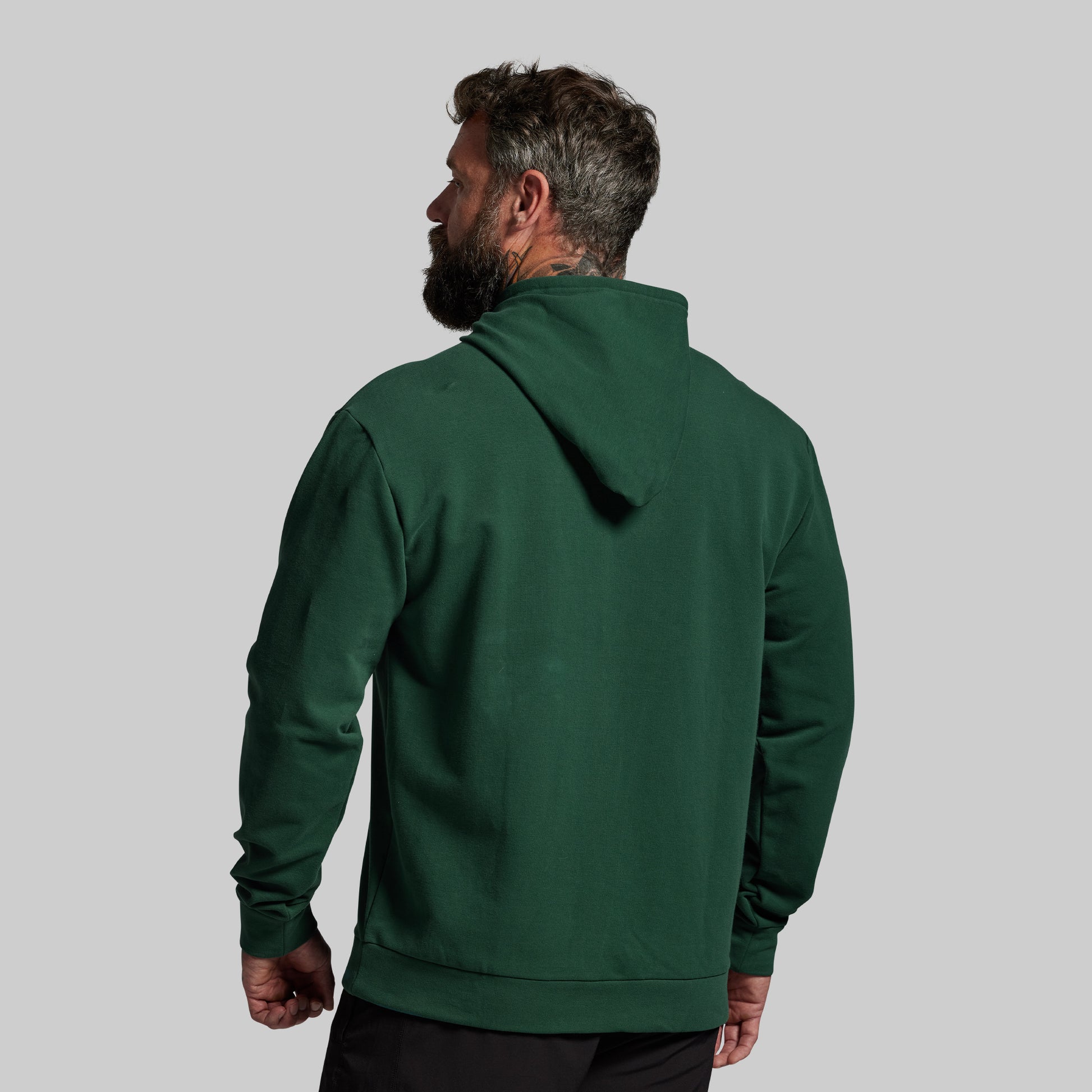 Man wearing a green hoodie from behind on a gray background