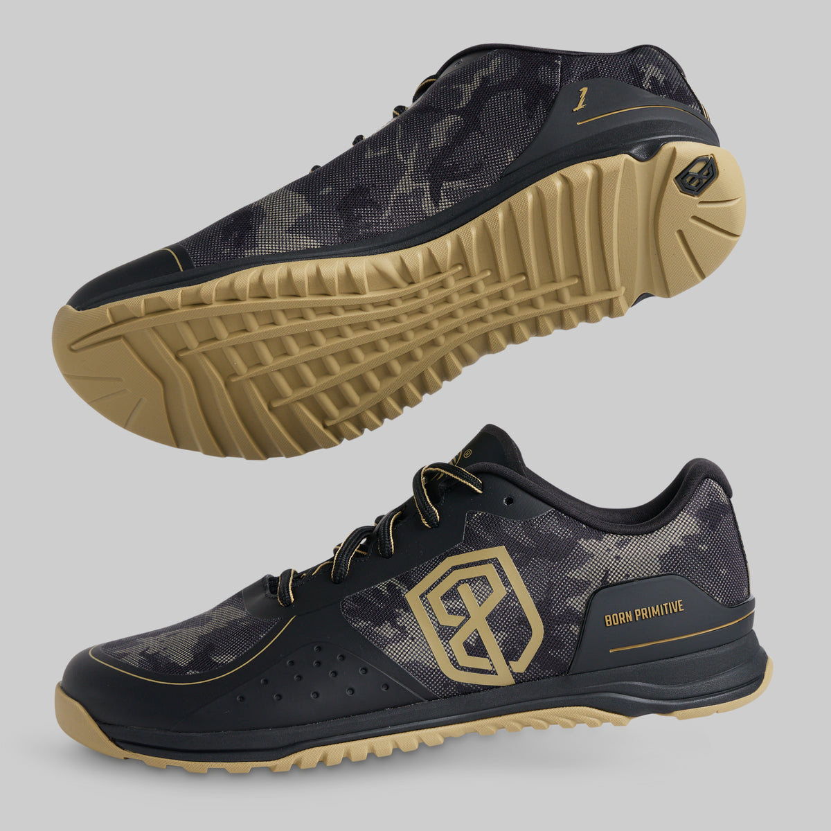 Two athletic shoes shown on a light gray background, one from the top view and one from the side profile. The shoes feature a black and dark gray camouflage pattern upper, black laces, a tan outsole, and gold accents including a large geometric logo on the side and 'BORN PRIMITIVE' text.