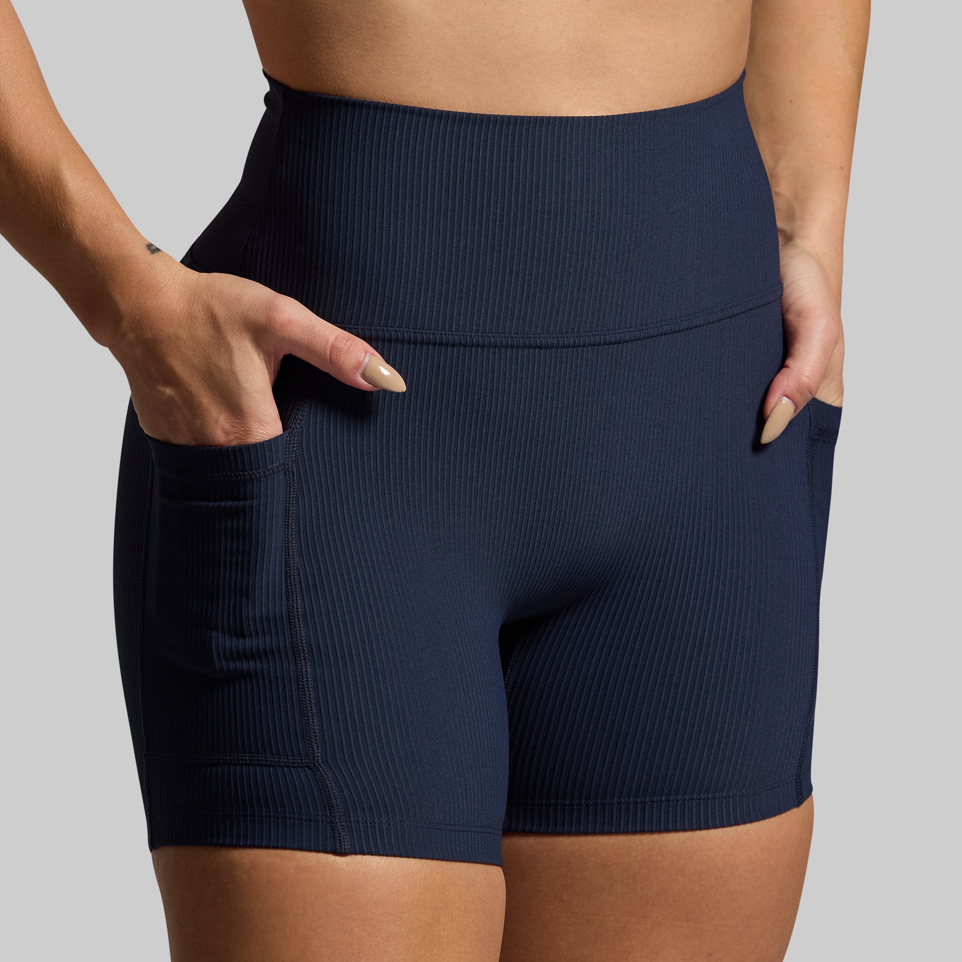 Navy blue ribbed shorts worn by a person on a gray background