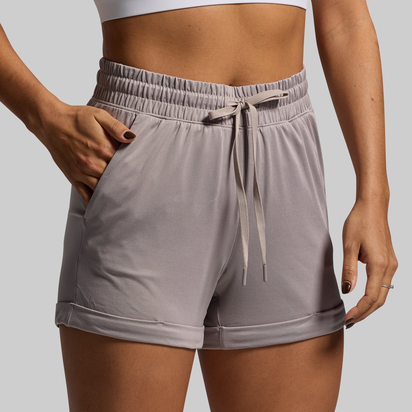 Person wearing gray shorts with a drawstring on a plain background