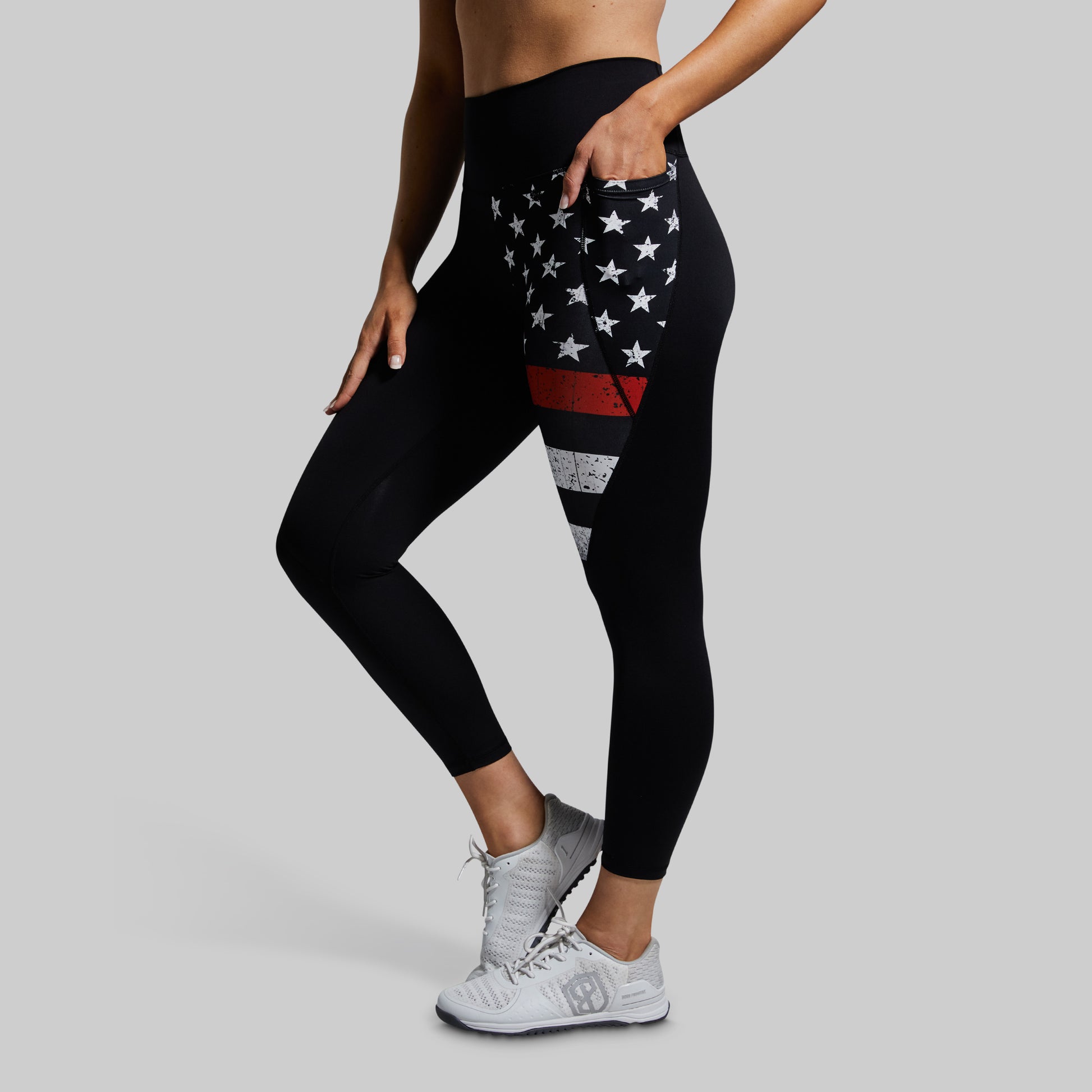 Black leggings with American flag design worn by a person on a gray background