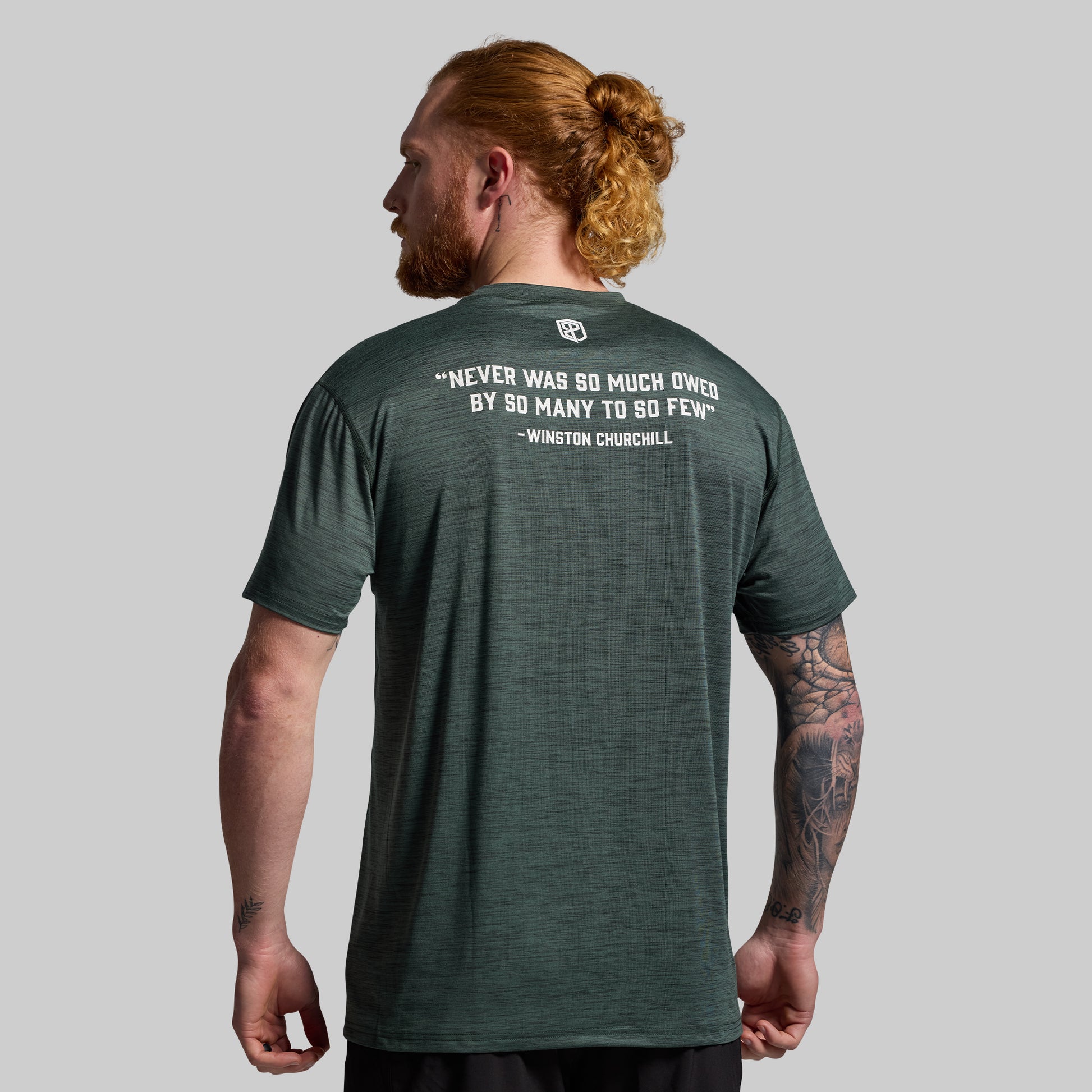 Man wearing a green t-shirt with a quote on the back against a gray background