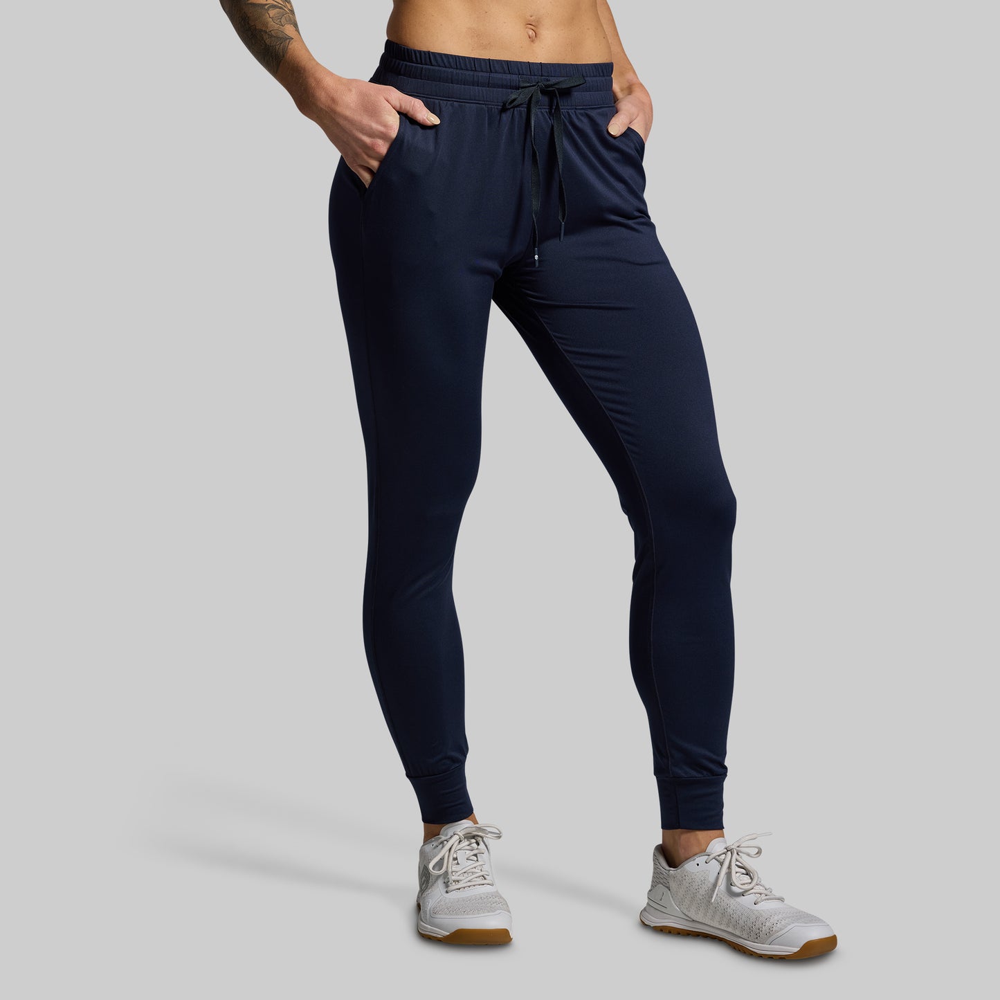 Navy jogger pants worn by a person on a gray background