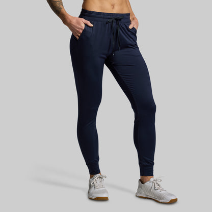Navy jogger pants worn by a person on a gray background