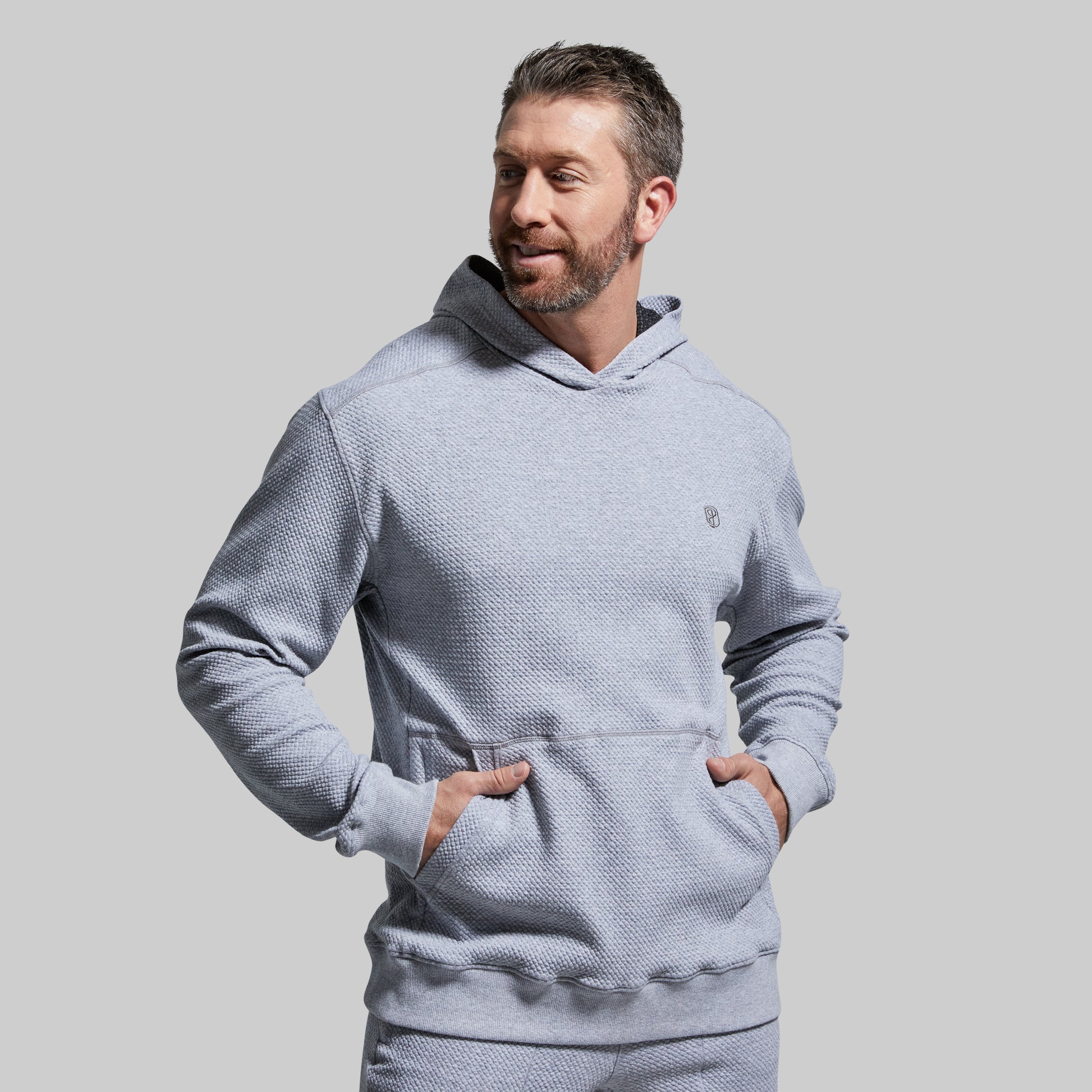Man wearing a light gray textured hoodie against a plain background