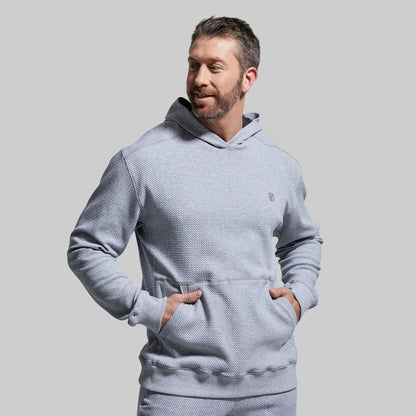 Man wearing a light gray textured hoodie against a plain background