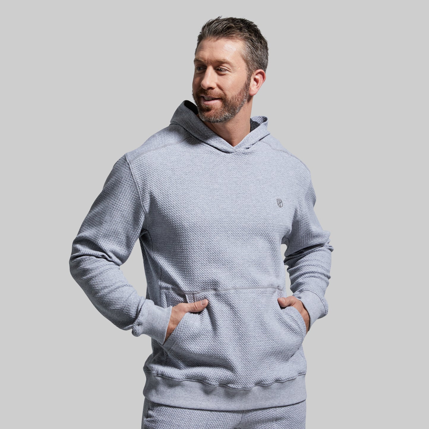 Man wearing a light gray textured hoodie against a plain background