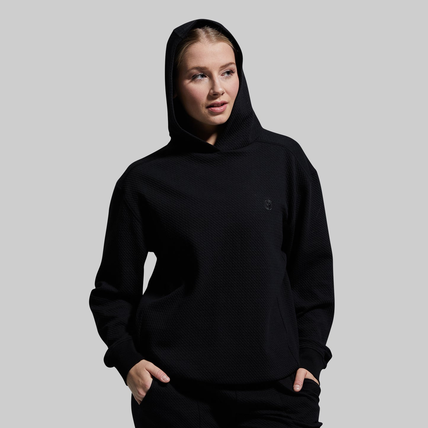 Person wearing a black hoodie on a gray background